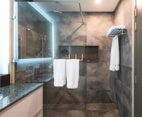 y baño con ducha y toallas blancas en la encimera. en Dusit Princess Hotel Residences Nairobi, en Nairobi