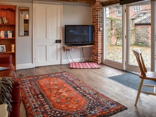 een woonkamer met een televisie en een tapijt bij The Dairy - Uk50885 in North Walsham