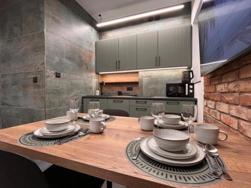 a kitchen with a wooden table with plates and wine glasses at Pod Palmami in Hel