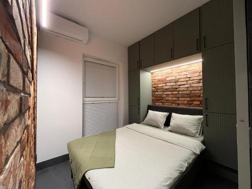 a bedroom with a bed and a brick wall at Pod Palmami in Hel