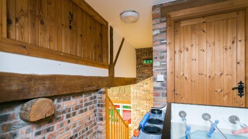 a kitchen with wooden cabinets and a brick wall at Llydaw in Pwllheli