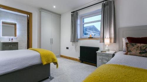 a bedroom with two beds and a window at Llydaw in Pwllheli