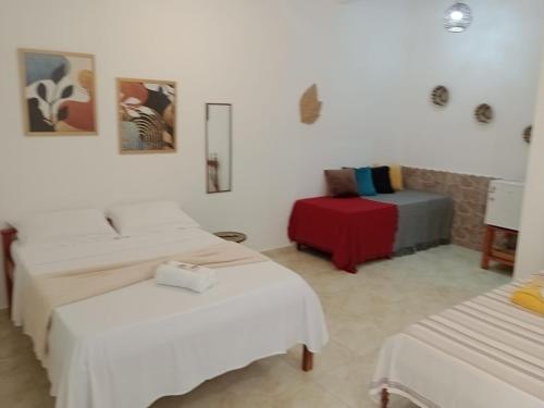 Una habitación blanca con dos camas y una silla. en Chalés Recanto das Flores RN, en Monte das Gameleiras