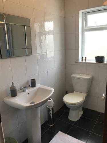 a white bathroom with a toilet and a sink at The Downtown Loft in Buncrana