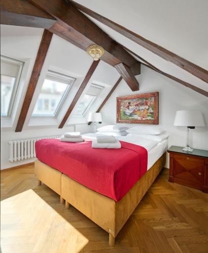 a bedroom with a large bed with a red blanket at Hotel Leon D´Oro in Prague
