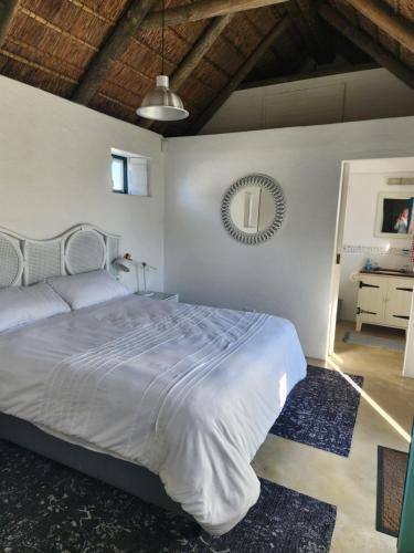 a bedroom with a white bed and a mirror at Hannah's Close in Struisbaai