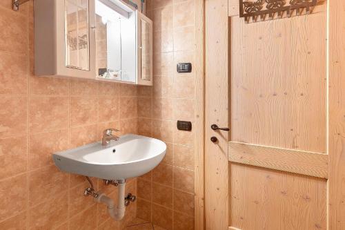 a bathroom with a sink and a mirror and a door at Agriturismo Quinto Quarto in Sondalo
