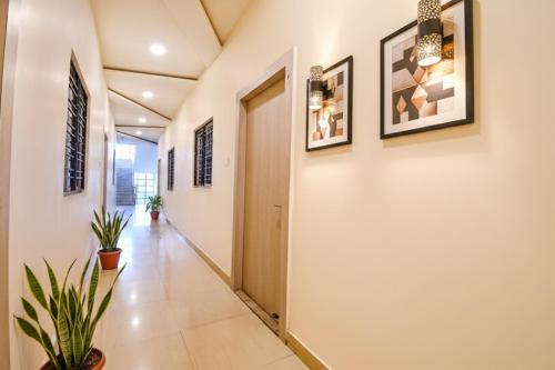 a hallway with white walls and a door and plants at FabHotel Kitchen Q Inn - Belaghata in Kolkata