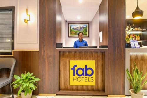 a woman standing behind a reception desk in a hotel lobby at FabHotel Kitchen Q Inn - Belaghata in Kolkata