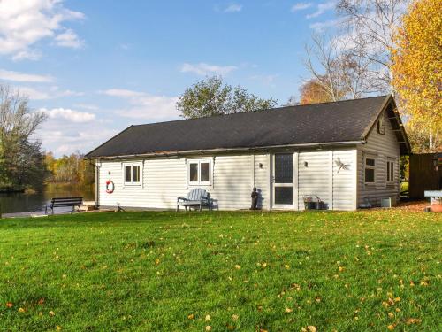 een wit gebouw met een zwart dak en een tuin bij The Boathouse - Uk50892 in Pentney
