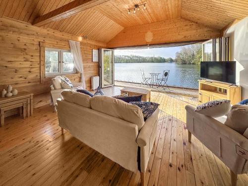 een woonkamer met banken en uitzicht op het water bij The Boathouse - Uk50892 in Pentney
