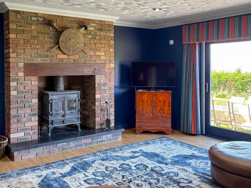 sala de estar con chimenea de ladrillo y TV en Abalone, en Culbokie