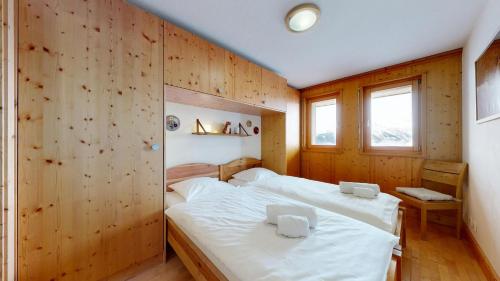 two beds in a room with wooden walls at Plein Ciel VA 032 - MOUNTAIN apartment 6 pers in Veysonnaz