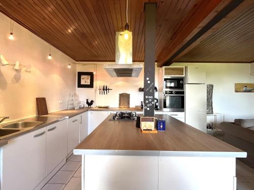 cocina con armarios blancos y techo de madera en Le Petit Four à Pain - Maison 4 personnes à la Campagne, en Neuvicq-Montguyon