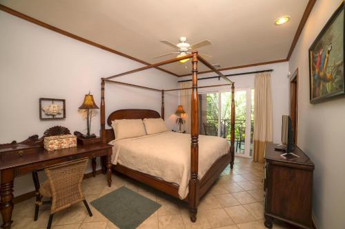 Veranda 2B 3 bdr Golf Course View in Los Suenos في هيرادورا: غرفة نوم بسرير مظلة ومكتب وتلفزيون