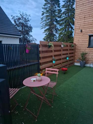 a pink table and chairs in a backyard with a fence at Maisonnette Rétro Loc in Amfréville