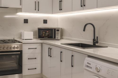 a white kitchen with a sink and a microwave at City Stay Dubai South - Serviced Apartments in Dubai