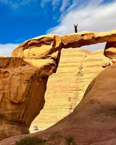 Ein Mann steht auf einer Felsformation in der Unterkunft Sunrise Echo Camp in Wadi Rum