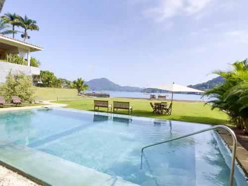a swimming pool with a view of the water at NOVO Mansão Pé na Areia com Heliponto, 1 Piscina, 1 Hidro, Sauna e 5 Quartos in Angra dos Reis