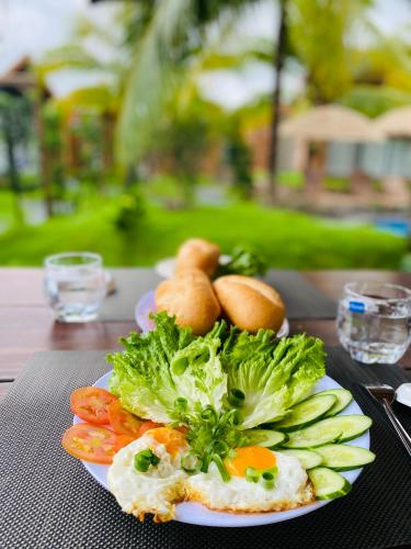 a plate of food with broccoli and vegetables on a table at Biển Tôm ốc Homestay Bến Tre - Hồ Bơi & BBQ Garden 