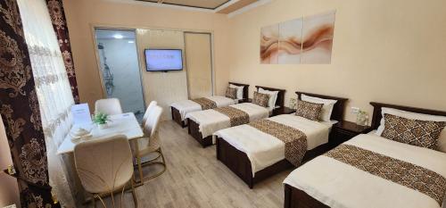 una camera d'albergo con quattro letti e una televisione di Guest house near Registan a Samarkand