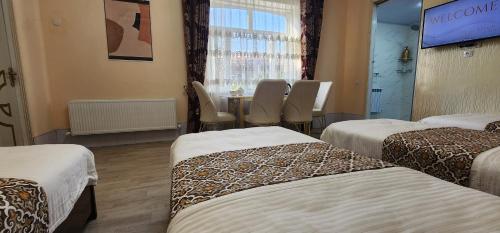 Guest house near Registan في سمرقند: غرفة بثلاث اسرة وطاولة مع كراسي