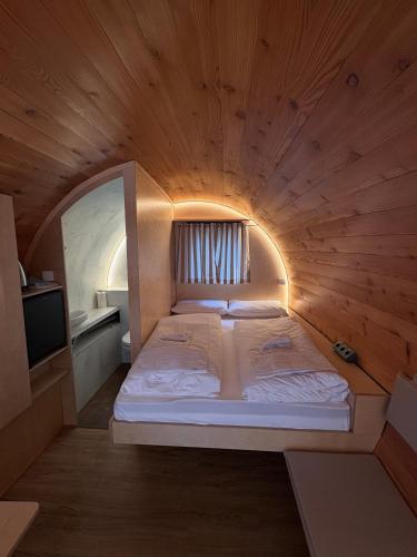 a large bed in a wooden room with a tv at Avalon Ferienpark Bad Bevensen in Bad Bevensen