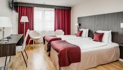 una habitación de hotel con dos camas y un escritorio en Hotell Nova, en Karlstad