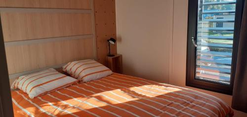 1 cama con 2 almohadas en una habitación con ventana en Chalet dans résidence privée avec piscine couverte, en Marzan