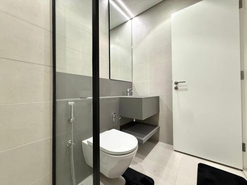 a bathroom with a toilet and a glass shower at Sahab - Masar 2BR Townhouse in Sharjah
