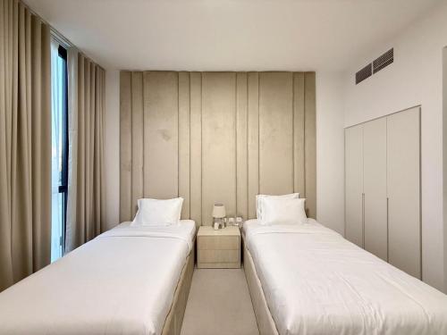 two beds sitting next to each other in a room at Sahab - Masar 2BR Townhouse in Sharjah