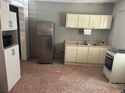 a kitchen with white cabinets and a stainless steel refrigerator at Aguada Get Away Apartment 