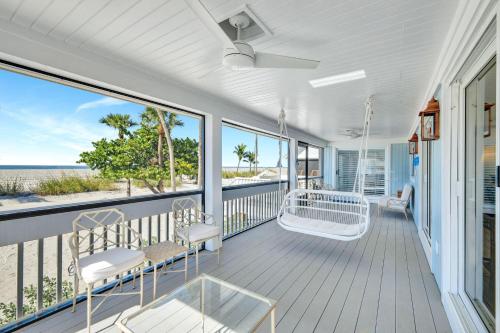 een kamer met een veranda met stoelen en een schommel bij South Seas Beach Home 10 in Captiva