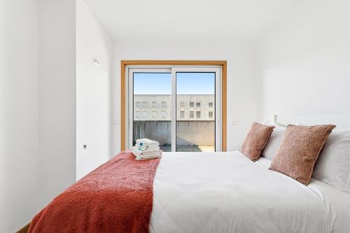 a bedroom with a large white bed with a large window at GuestReady - Terrace Cozy Stay in Coimbra