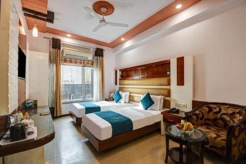 um quarto de hotel com duas camas e um sofá em Hotel Star Plaza - 1 Minute From New Delhi Railway Station & Connaught Place em Nova Deli