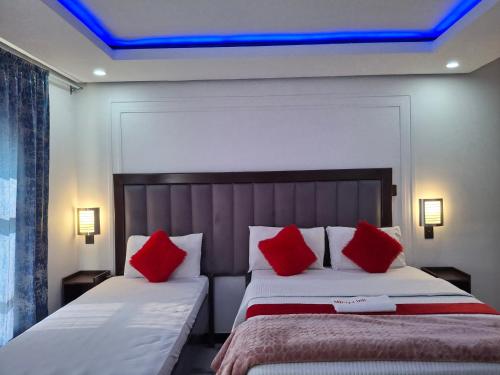 a bedroom with two beds with red pillows at Mbuya Express Inn in Manzini