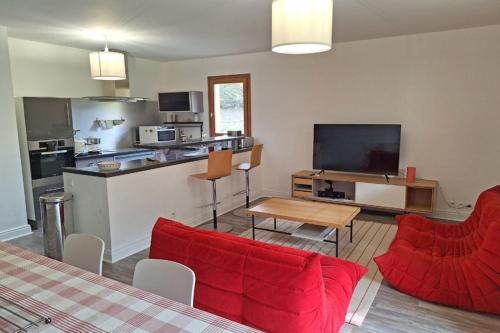a living room with a red couch and a kitchen at Modern apartment in the heart of Séez in Séez