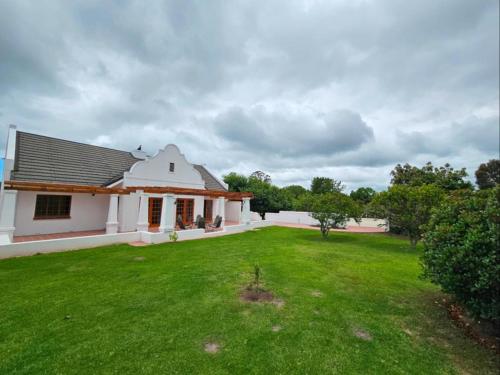 a white house with a large green yard at Wingrock Guesthouse in George