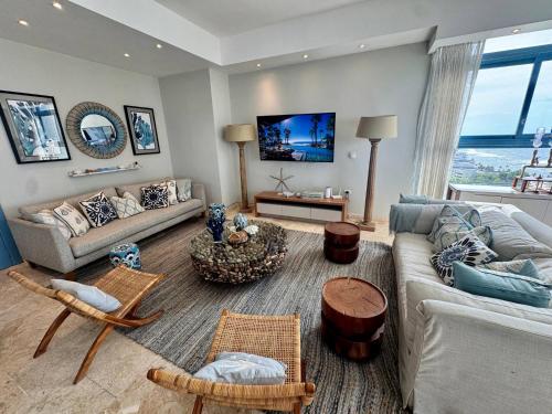 JuanDolio Penthouse 3 bedrooms Beachfront frente a hemingway في Los Corrales: غرفة معيشة بها أريكة وطاولة