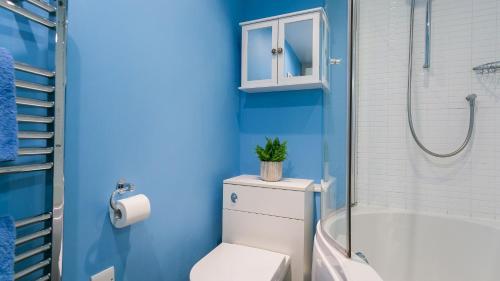 a blue bathroom with a toilet and a shower at Hafan in Beaumaris