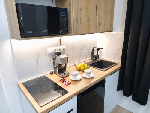 a kitchen counter with a sink and a microwave at Belvárosi Lux Apartman in Vásárosnamény