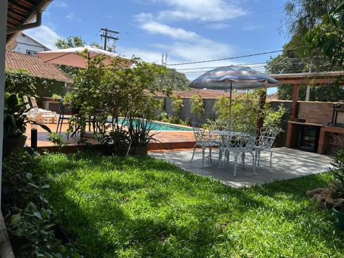 a patio with a table and an umbrella in the yard at Casa da Árvore Bertioga in Bertioga