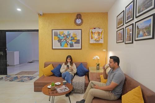 a man and woman sitting on a couch in a living room at FabHotel Rajtilak in Ahmedabad