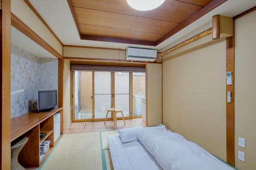 a living room with a bed and a television at Katsuzakikan in Tsubata
