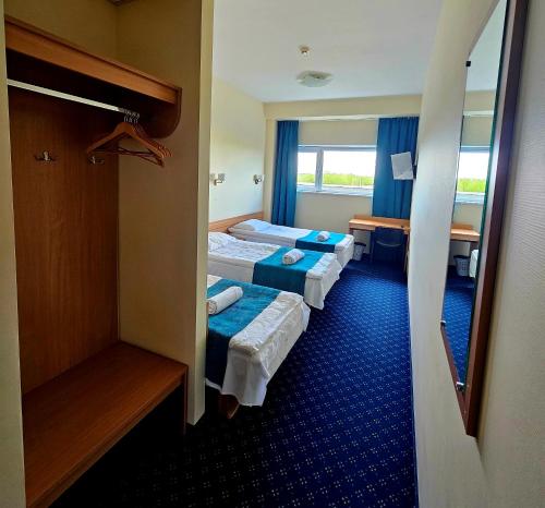 a hotel room with three beds and a window at Via Baltica Panevezys Self Check-in Hotel in Panevėžys