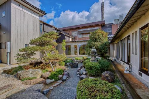 a garden in front of a building with a tree and rocks at Katsuzakikan in Tsubata