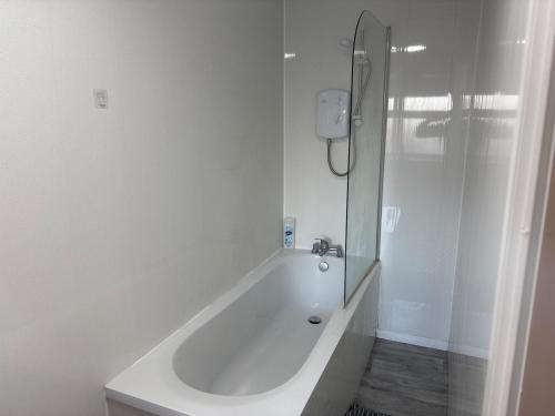 een witte badkamer met een bad en een douche bij Zinoc Seaside Apartment in Murton