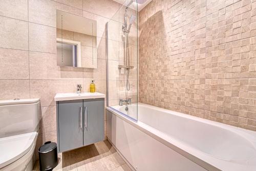 a bathroom with a tub and a sink and a toilet at Central and Stylish, Garden and Parking in Coventry