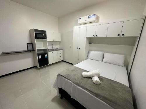 a white bedroom with a bed and a kitchen at Cabanos Prime Hotel e Residencial in Barcarena