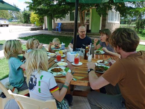 MweigaAberdare Juniper Green Gardens Resort的一群人围坐在桌旁吃饭